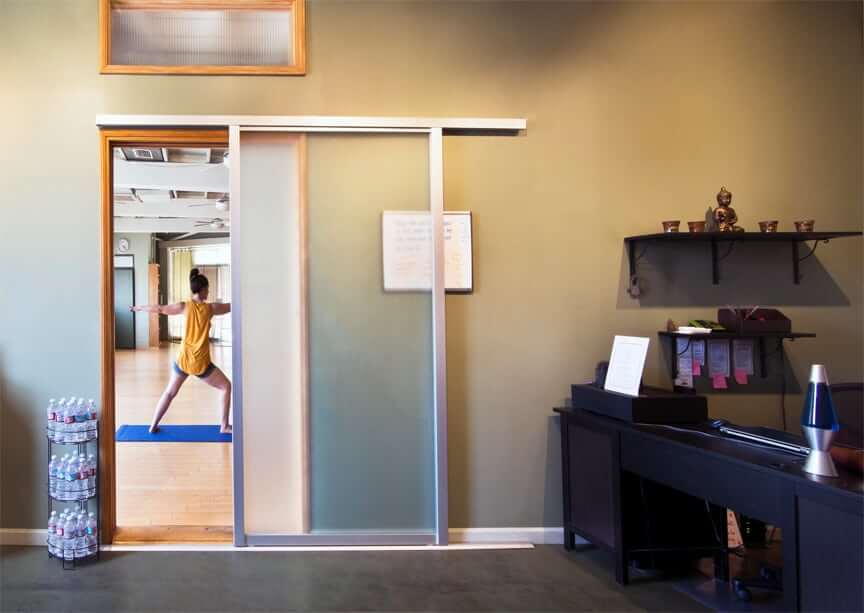 A person steps through a sliding glass door at a yoga studio.