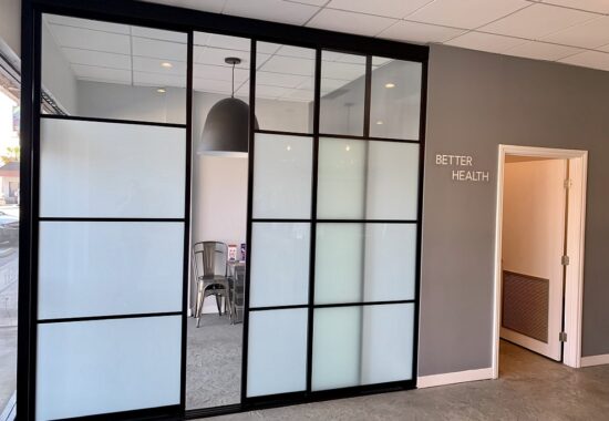 Modern office partition with frosted glass doors and a door sign reading "better health.