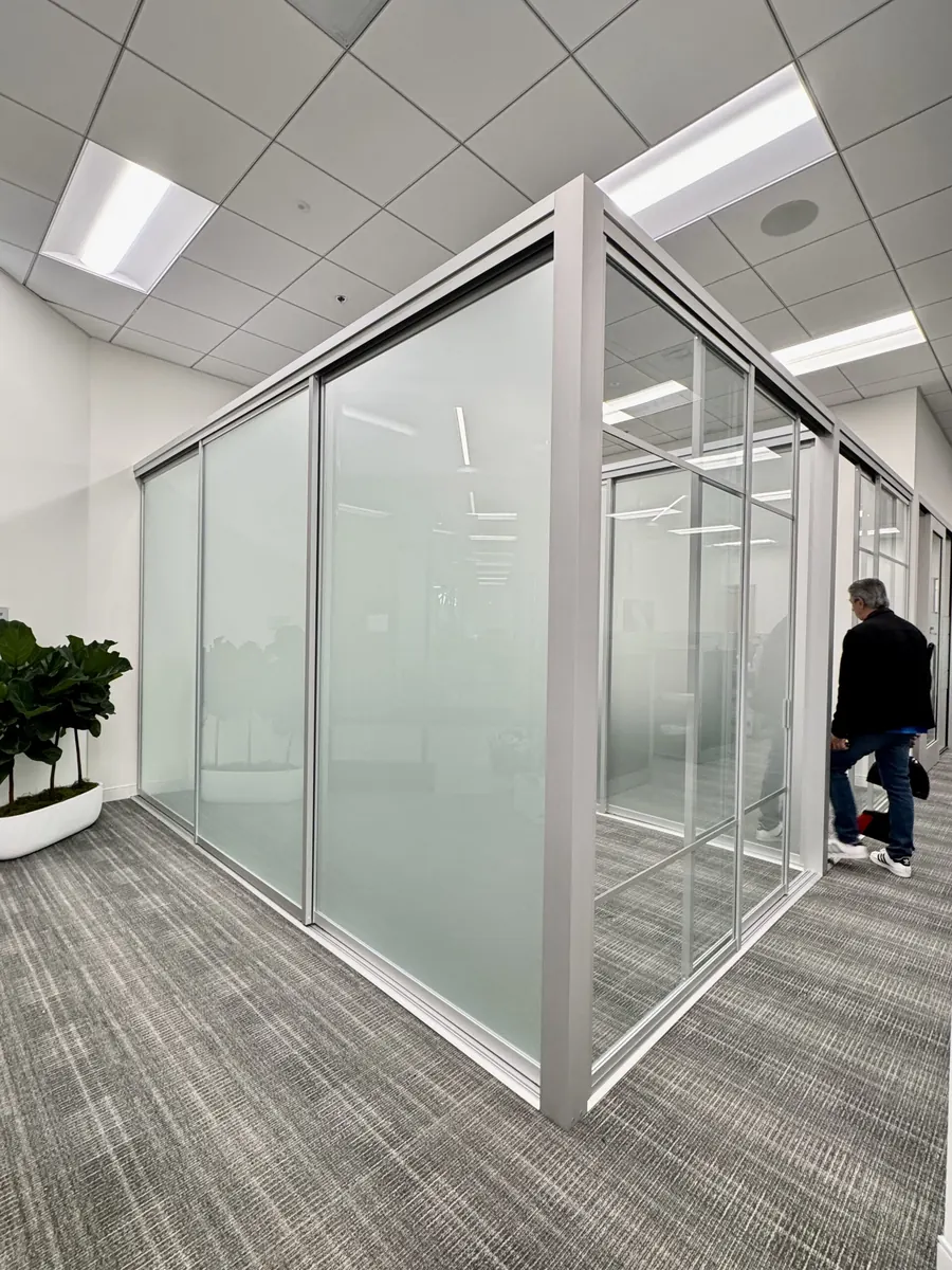 Glass office enclosure with silver framing, frosted panels, and a sliding entry door